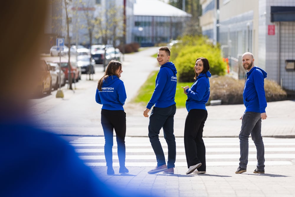 Combitech employees two men and two women walking outside with Combitech hoodies.